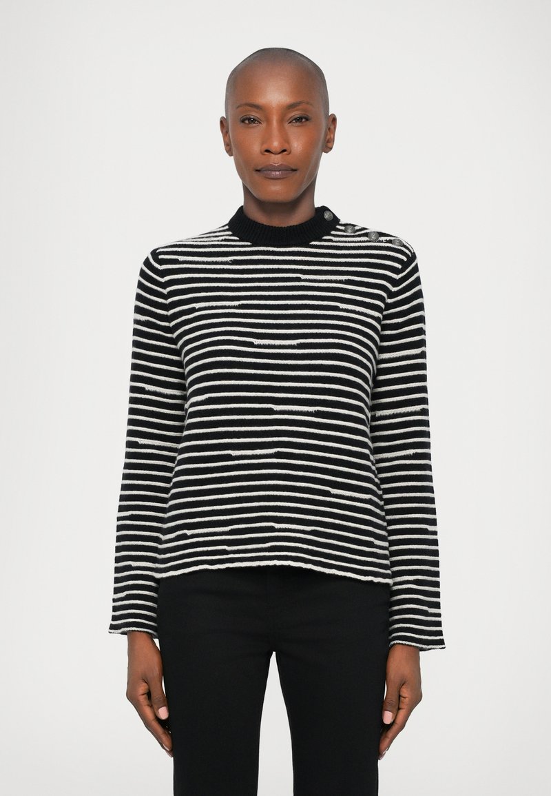 Maglione a strisce bianche e nere con maniche lunghe, colletto a coste e orlo leggermente corto. Il tessuto appare testurizzato con dettagli a maglia.