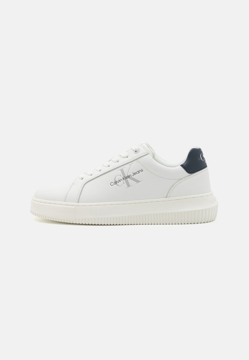 Fehér bőr sneaker kerek orral, texturált gumitalppal és sötétkék kiegészítővel a sarkán. Diszkrét logó található az oldalán.