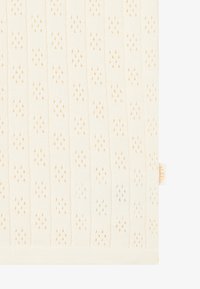Lys kremfarget strikket tekstil med et mønster av små diamanter og dråper i dempet oransje. Inkluderer et lite gult merkelapp.