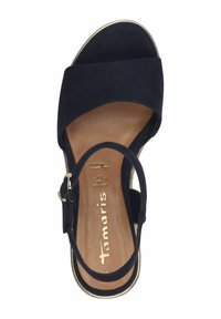 Sandal in suede blu navy con una larga fascia frontale, fibbia alla caviglia e un'intersuola liscia color beige. Presenta un tacco basso e dettagli circolari sui bordi.