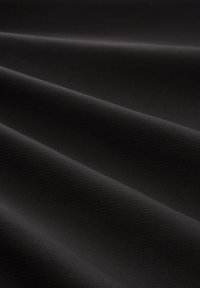 Black fabric with a smooth, matte texture featuring subtle diagonal lines, draped in soft folds, highlighting its flexibility and sheen.