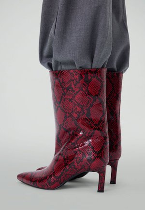 Red and black snakeskin-patterned ankle boots with a glossy finish, pointed toe, and a small, tapered heel. Textured material.