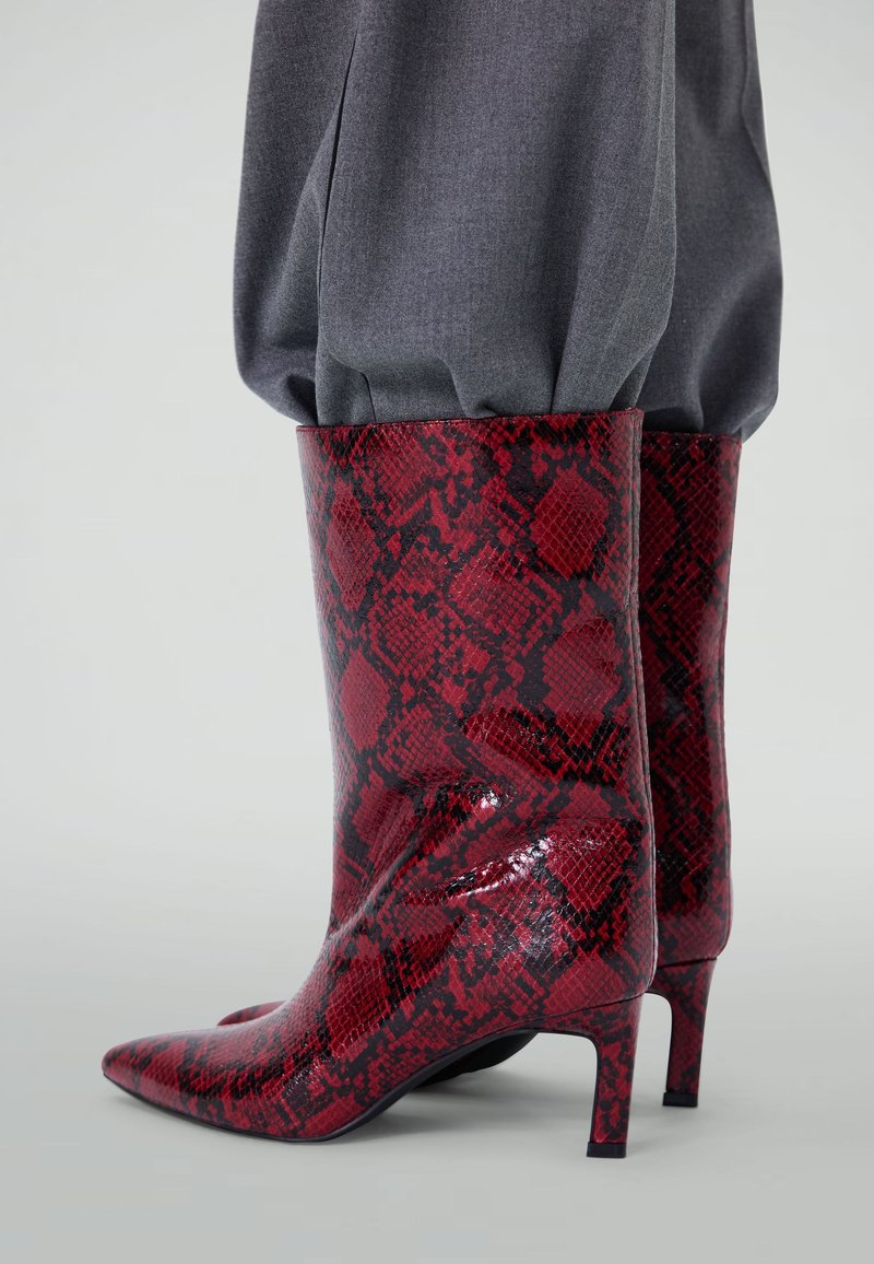 Red and black snakeskin-patterned ankle boots with a glossy finish, pointed toe, and a small, tapered heel. Textured material.