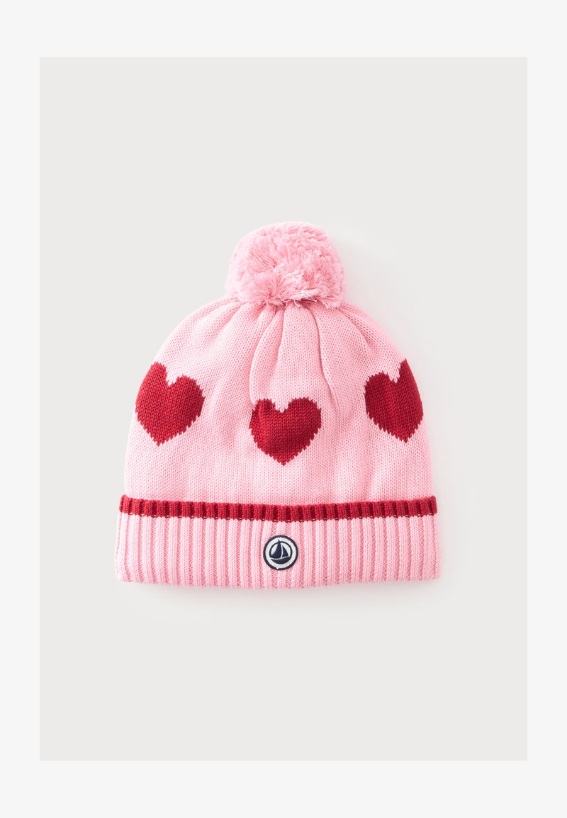 Bonnet en tricot rose avec trois cœurs rouges, un pompon sur le dessus et un petit logo rond sur le bord côtelé.