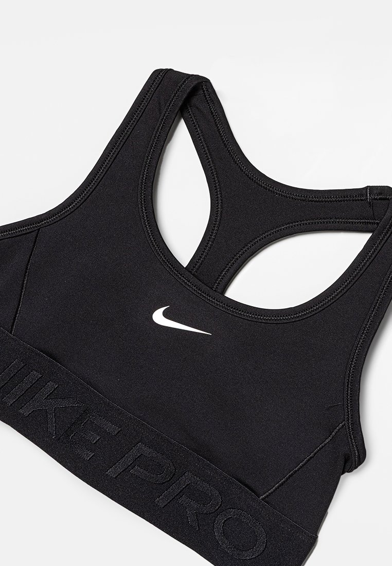 Reggiseno sportivo Nike Pro nero con logo swoosh bianco sulla parte anteriore e design a racerback, poggiato su uno sfondo bianco.