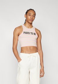Striped crop top in pastel colors features a black "PROUD TO BE" graphic. Paired with light-colored, loose-fitting pants.