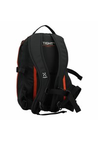 Mochila negra con acentos naranjas, diseño ergonómico, correas ajustables y un panel trasero acolchado etiquetado como "TIGHT™ X SMALL". Material durable.
