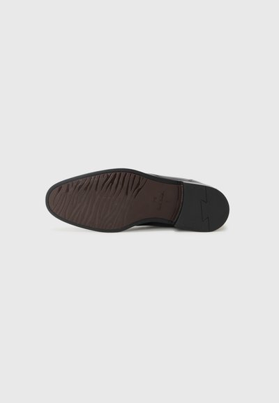 Semelle de chaussure en cuir noir avec un motif texturé en vagues en caoutchouc brun foncé. Forme carrée avec une légère courbure au niveau du bout.