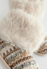 Strickslipper mit einem Fellbund, der ein mehrfarbiges Muster aus Creme, Braun und Türa zeigt. Enthält ein kleines Etikett mit "NEXT."
