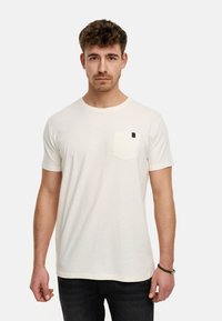 Cremefarbenes kurzärmliges T-Shirt mit einer linken Brusttasche und einem runden Halsausschnitt, aus einem weichen Stoff mit lässiger Passform.