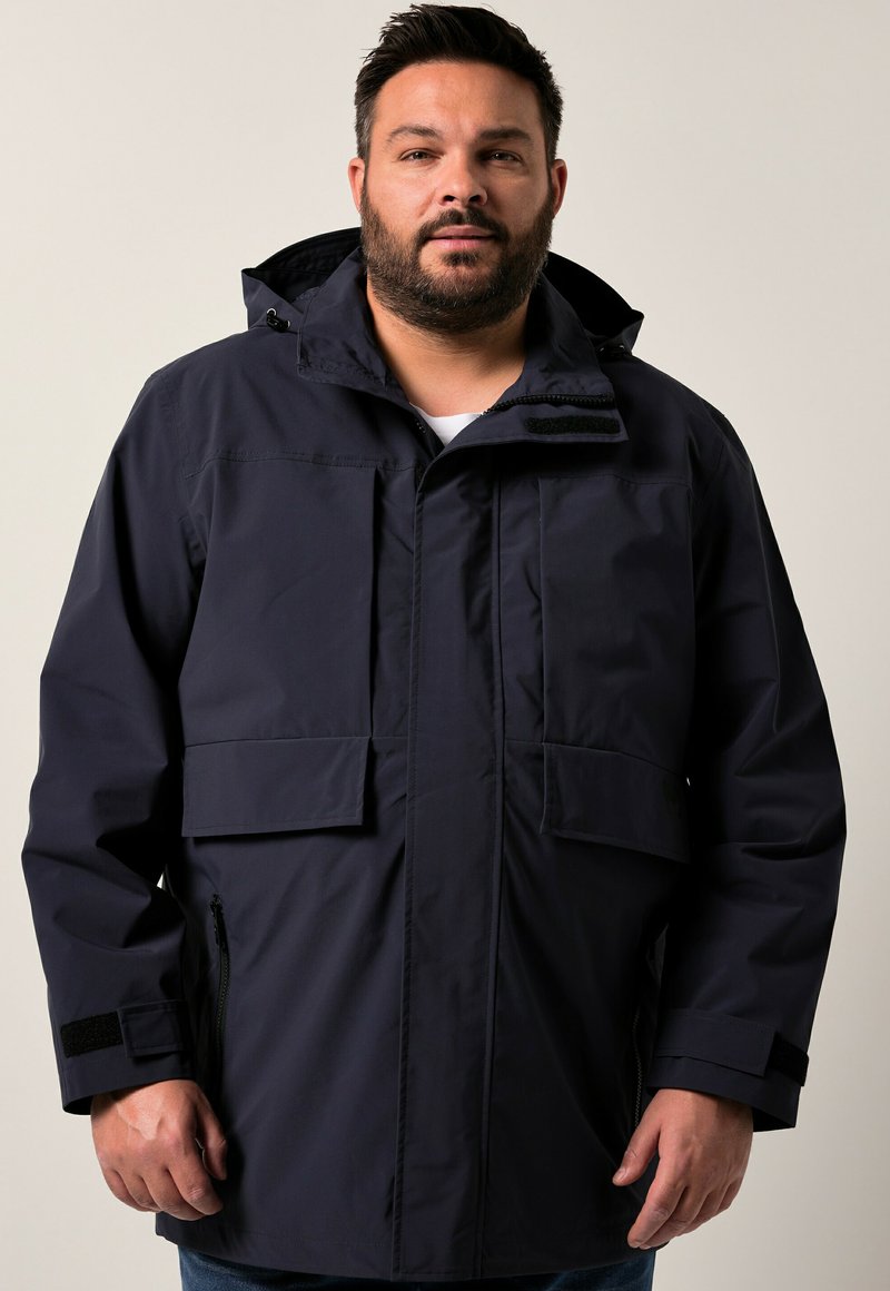 Námornícka nepromokavá bunda má kapuci, dvě přední kapsy a manžety na suchý zip. Materiál je hladký s matným povrchem.