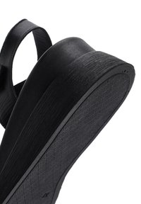 Sandalo con zeppa nera che presenta una suola in gomma texturizzata, un materiale superiore liscio e una fascia larga per il supporto. Profondità e contorno sono visibili nel design.