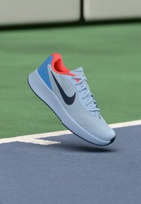 Light blue running shoe with a breathable mesh upper, black Nike swoosh, orange accent on the collar, and a textured black sole.