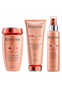Kérastase Discipline haircare trio includes a pink shampoo jar, conditioner tube, and leave-in fluid. Features silver and gold accents.