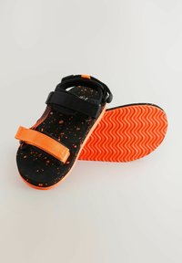 Čierne sandále s oranžovými akcentmi a posiakovaným detailom. Obsahujú nastaviteľné popruhy a textúrovanú oranžovú podrážku pre lepšiu priľnavosť.