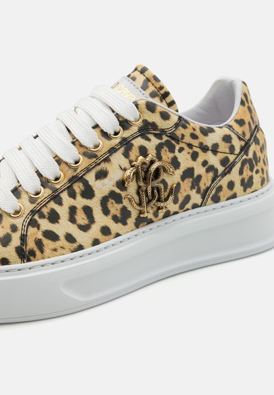 Tenisky s leopardím vzorom a lesklým povrchom, biele šnúrky, zlatý akcent loga a hrubá biela podrážka. Textúrovaná látka s viditeľnými vzormi.