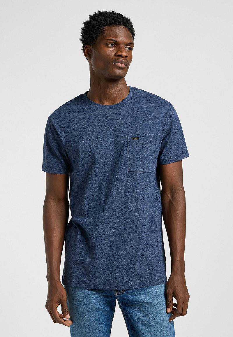 Marinblå crew neck t-shirt i strukturerad tyg, har en bröstficka med en liten logotyp. Bärs med blå jeans.