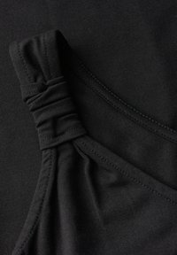 Czarna tkanina o gładkiej fakturze, z ozdobnym detalem w formie marszczenia na pasku. Zawiera przeszycia wzdłuż krawędzi.