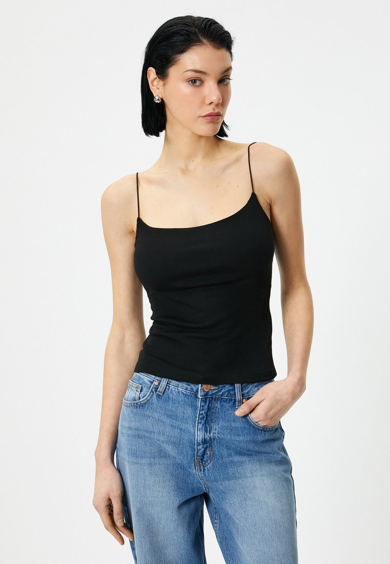 Zwarte stretch camisole met dunne bandjes en een ronde halslijn, gecombineerd met lichtblauwe high-waisted jeans. Glad materiaal met een getailleerde silhouet.