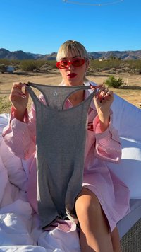 Grijze tanktop met een ronde hals en een slanke pasvorm. De stof lijkt zacht met een subtiele textuur. Vastgehouden tegen een woestijnachtergrond.