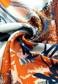 Zijde stof met een levendig bloemmotief in oranje, marineblauw en wit, met een zachte textuur en ingewikkelde details.