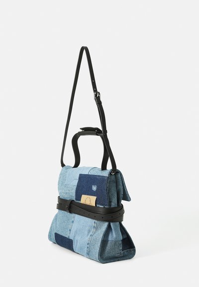 Geantă de umăr din denim patchwork cu detalii din curea de piele și curea ajustabilă din piele neagră pe fundal alb.