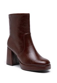 Bottine en cuir marron avec une surface texturée, bout carré et un talon épais. Présente des coutures minimales et un design épuré.