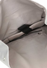 Harmaa kangaspussin sisäosa, jossa on sileä pinta, vetoketjullinen tasku ja mustalla hihnalla varustettu lokero.