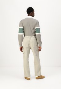 Gray long-sleeve shirt with white and green stripes, paired with light beige cargo pants featuring multiple pockets and elastic waistband.