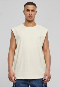 Sømløs beige bomulds t-shirt med rund hals, afslappet pasform og glat tekstur, båret med mørk denim cargo shorts.