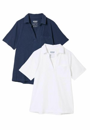 Zwei Polohemden: eines in Marineblau und eines in Weiß. Beide haben kurze Ärmel, einen Kragen, eine Tasche auf der linken Brust und eine lockere Passform.