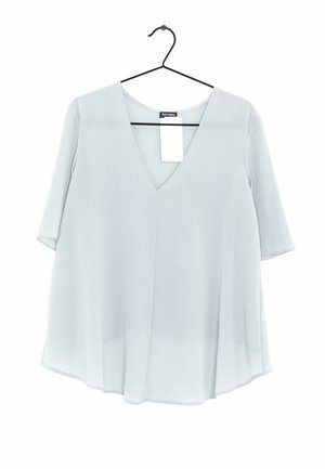 Light blue, loose-fit blouse with V-neck and half sleeves hanging on black hanger against white background.