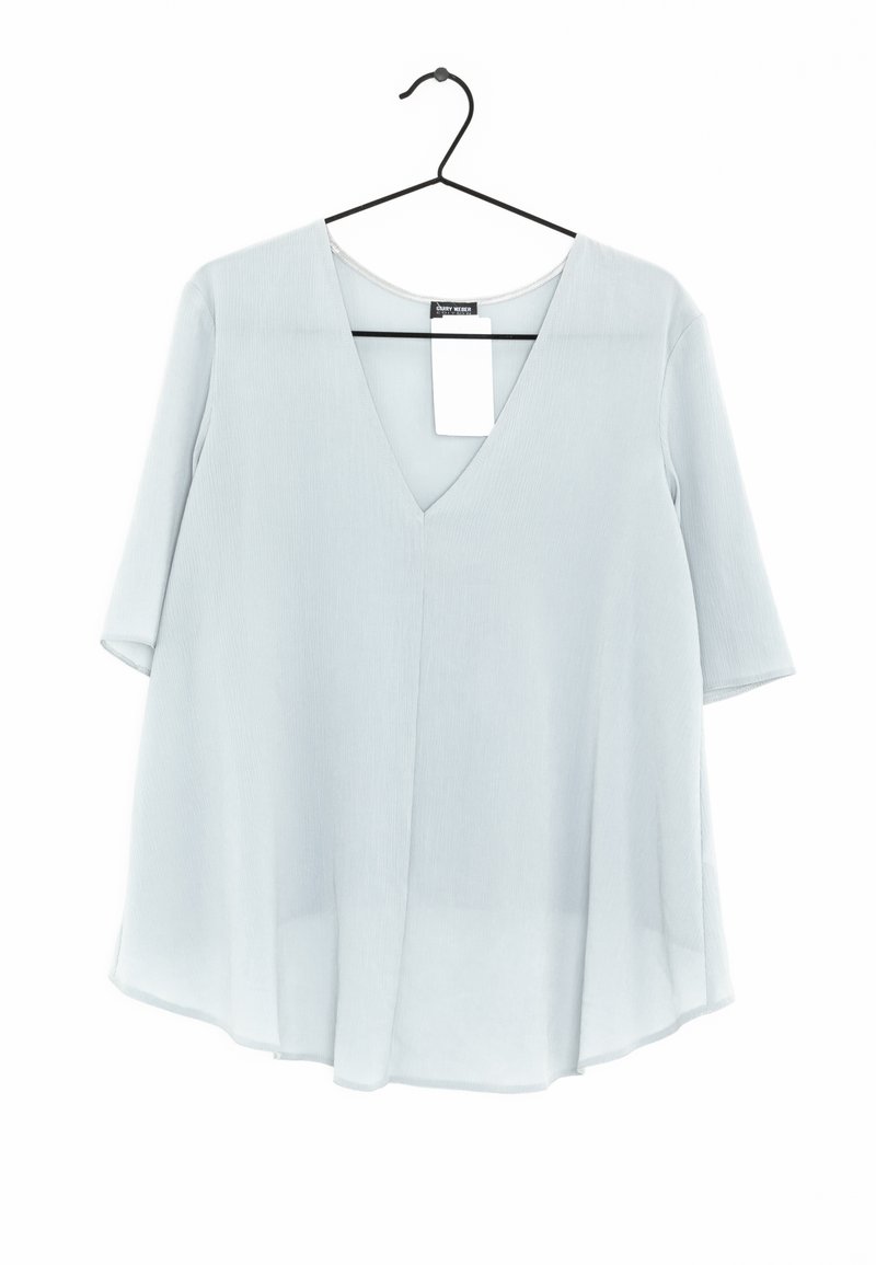 Blouse bleu clair, à coupe ample, avec décolleté en V et manches courtes, suspendue sur un cintre noir contre un fond blanc.