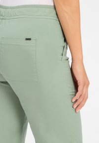 Lichtgroene, lichte broek met een elastische tailleband, zijzakken en een enkele achterzak. Glad textuur, casual pasvorm.