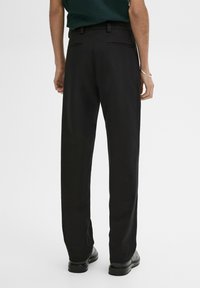 Pantaloni neri con taglio dritto, tasche laterali e posteriori, e una texture di tessuto liscia. Rifiniti con un punto vita standard e passanti per cintura.