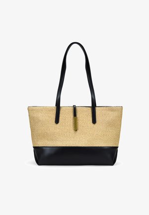 Bolsa de tote de paja trenzada con fondo y asas de cuero sintético negro. Presenta una pestaña de acento dorado en el centro superior. Superficie texturizada.