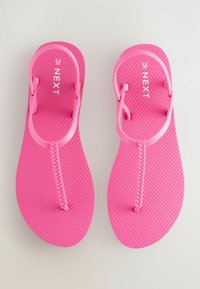 Vaaleanpunaiset flip-flopit, joissa on teksturoitu pohja ja punotut hihnat. Keveitä ja valmistettu joustavasta materiaalista. Koko ilmoitettu 6,5/40.