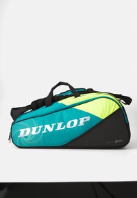 Dunlop sporto krepšys mėlynavo ir juodos spalvos, su geometriniu raštu, dideliu sidabriniu logotipu, paminkštintomis rankenomis ir tvirtu užtrauktuku.
