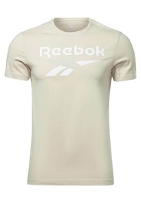 Beige Reebok t-shirt med rund halsringning, korta ärmar och en stor vit logga över br östet. Tillverkad av ett mjukt och slätt tyg.