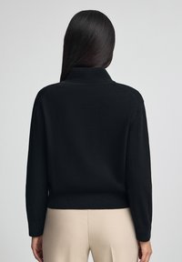 Svart stickad tröja med hög krage, långa ärmar och ribbat nederkant. Slät textur. Enkel design, inga synliga mönster eller accenter.