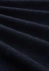 Ciemnoniebieski materiał tekstylny o miękkiej, teksturowanej powierzchni, z widocznymi równoległymi liniami i delikatnymi fałdami, co wskazuje na lekki materiał.