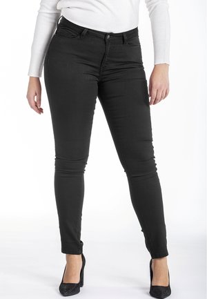Jean skinny noir en denim extensible. Présente une taille mi-haute, cinq poches et une coupe ajustée jusqu'à la cheville.