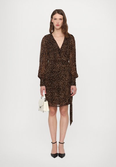 Rochie în imprimeu leopard, cu mâneci lungi, decolteu adânc în V, talie strânsă și detaliu legat. Asortată cu o geantă mică albă și pantofi cu toc negri.