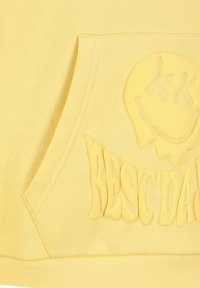 Gelbe Kapuzenjacke mit weicher Textur, die auf der Vorderseite der Tasche ein erhabenes Smiley-Gesicht und den Text "RESC DAD" in einem gewellten, erhabenen Design zeigt.