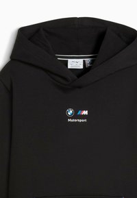 Sudadera negra con bolsillo frontal, que presenta un logo de BMW y el texto "Motorsport". La tela es suave, con un corte estándar y capucha con cordón.