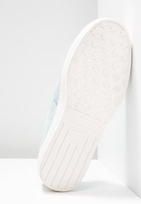 Semelle de sneaker en daim bleu clair avec un fond en caoutchouc blanc comportant un motif de traction en forme d'étoile et une marque en relief. Taille 37 indiquée.