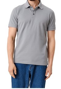 Polo gris avec un col classique, patte de boutonnage à trois boutons, manches courtes et texture lisse, associé à un jean en denim bleu.