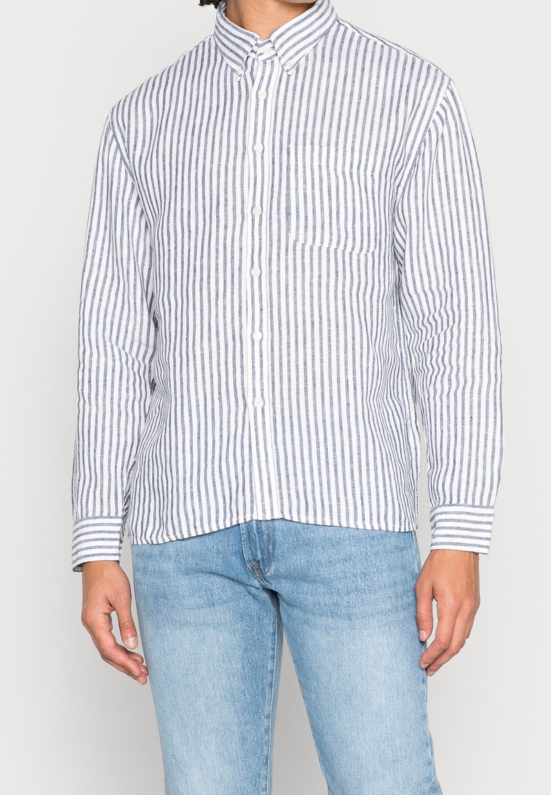 Camicia a righe in azzurro chiaro e bianco, realizzata in tessuto intrecciato, con taschino sul petto e maniche arrotolate.