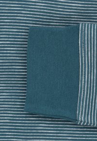 Gestreepte stof in teal en wit met een effen teal accent. Zachte textuur. Close-up van het patroon en het kleurcontrast in het materiaal.