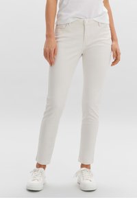 Ljusbeiga slim-fit jeans tillverkade av en bomullsblandning, med knappstängning, fem fickor och vita sneakers. Slät textur.